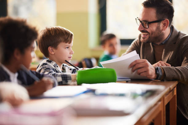 istock Happy professor talking to schoolboy on a class at school. 2204838002