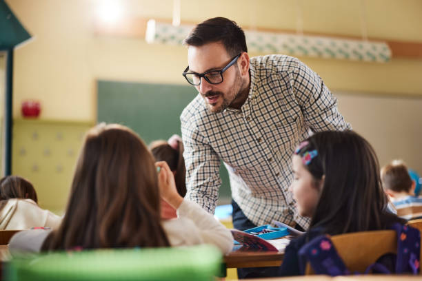 istock Male professor assisting his elementary students on a class at school. 2204838015
