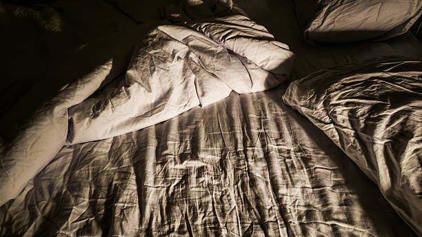 istock A messy bed with wrinkled sheets and high contrast at night 2204843081