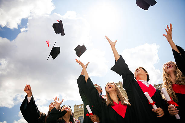 istock Young graduates celebrate with joy throwing mortarboards into the sky on a sunny day, marking the completion of their academic journey. 2204845334