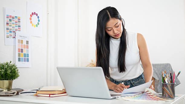 istock An asian woman is leaning over the table to read the documents placing among working materials. 2204848486