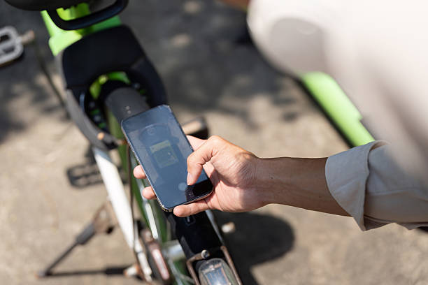 istock Smart Cycling and Modern Commuting. A young man uses his smartphone while preparing to ride a green bicycle, highlighting the functions of smart commuting. 2204850964