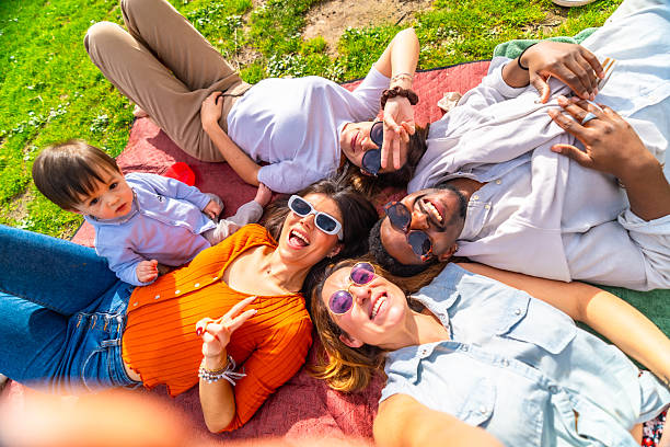istock Happy friends taking selfie, lying on grass in park during sunny day 2204852645