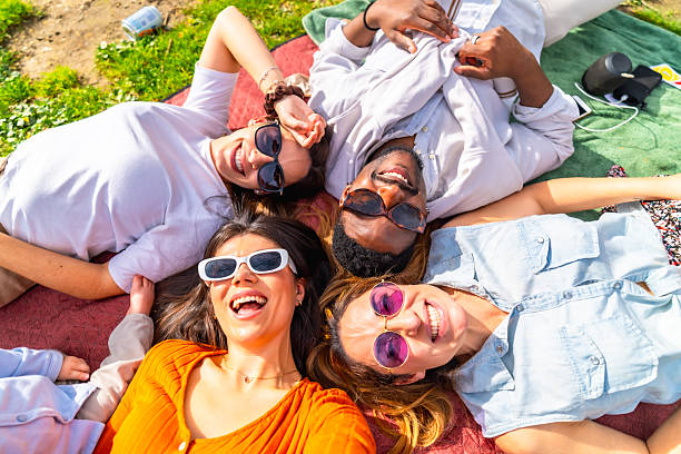 istock Happy friends lying on blanket taking selfie at park 2204852668
