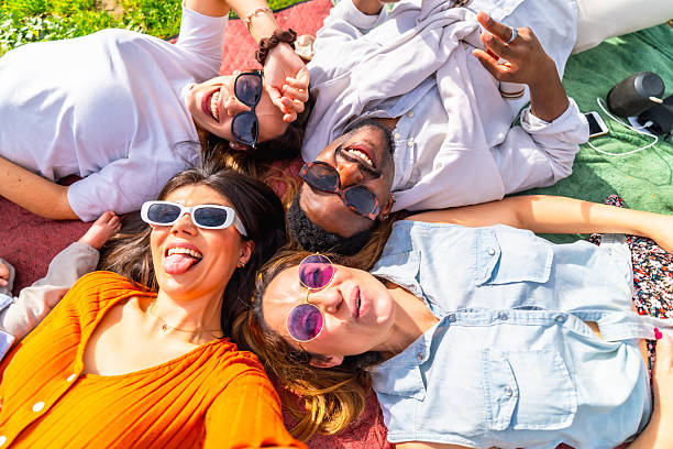 istock Group of friends lying on blanket taking a selfie and making funny faces 2204852687