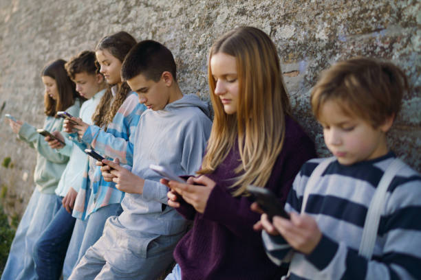 istock Children leaning on a wall and using mobile phones 2204853851