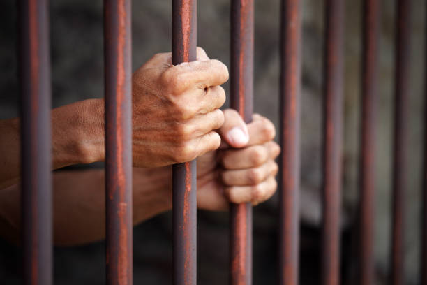 istock Hands Grasping Rusty Metal Bars of a Prison Cell in Close Up 2204854415