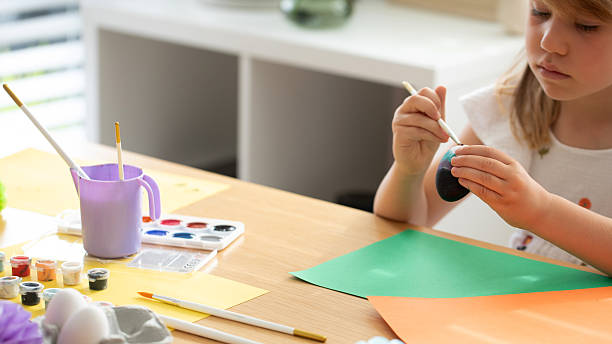 Child enjoying creative painting of Easter eggs in sunny room. Happy Easter