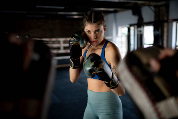 istock Female boxer training with focus mitts in gym 2204858110