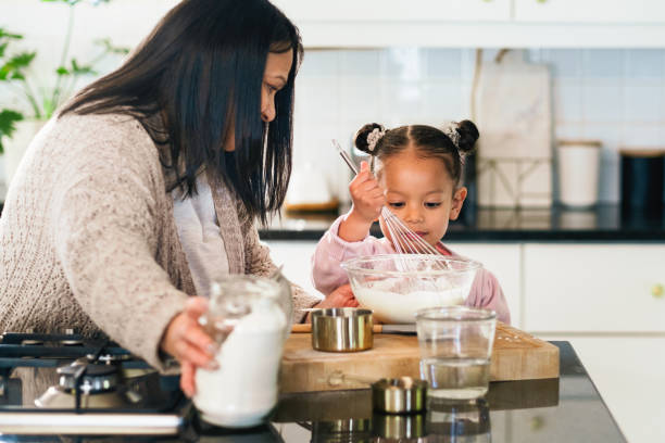 istock Baking, kitchen or recipe with mother and daughter in home together for development or learning. Cooking, food or ingredients with woman parent teaching girl child how to prepare dessert or pastry 2204861804