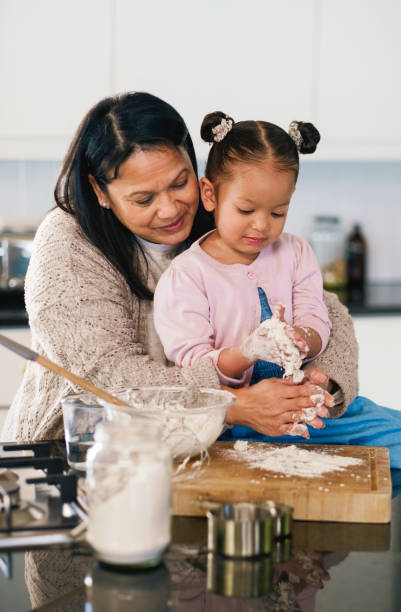 istock Baking, kitchen or recipe with granny and girl in home together for development or learning. Cooking, food or ingredients with woman grandparent teaching grandchild how to prepare dessert or pastry 2204861812