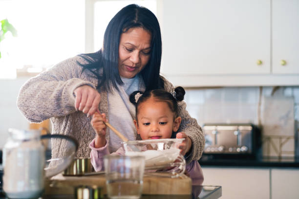 istock Baking, ingredients or kitchen with granny and grandchild in home together for development or learning. Cooking, food or recipe with senior woman teaching girl kid how to prepare dessert or pastry 2204861824