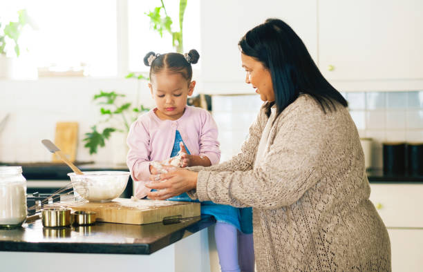 istock Baking, kitchen or recipe with granny and grandchild in home together for development or learning. Cooking, food or ingredients with senior woman teaching girl child how to prepare dessert or pastry 2204861829