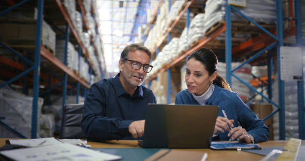 Logistics, laptop and people in warehouse for teamwork, shipping distribution or organizing cargo. Manger, procurement task or factory workers checking for delivery order, stock or ecommerce parcel