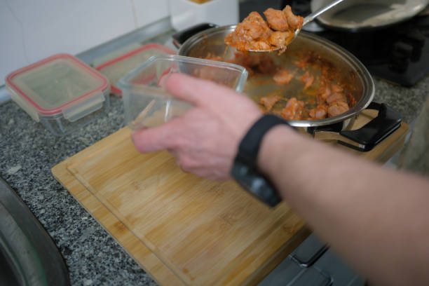 Chef is putting leftovers in a glass food container in a kitchen