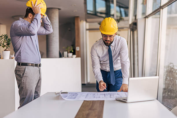 istock Architects reviewing blueprints in modern office with laptop 2204869768