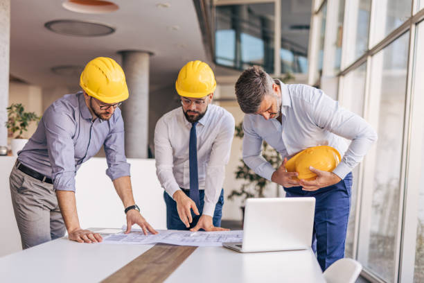 istock Architects examining blueprints in modern office, one having back pain 2204869938