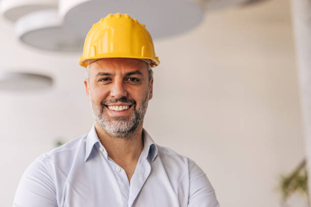 istock Smiling engineer wearing yellow hard hat in modern office 2204870517