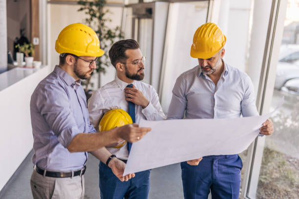 istock Engineers and architects reviewing blueprint plans in office 2204871362