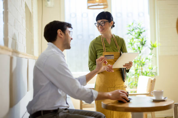 istock Happy Asian waitress charging to a man for the coffee 2204871885
