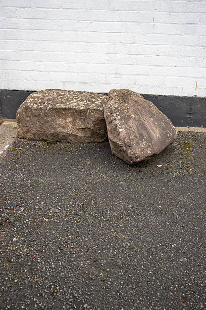 istock large grey boulders rocks placed next to tarmac road to security stop parking and access 2204873951