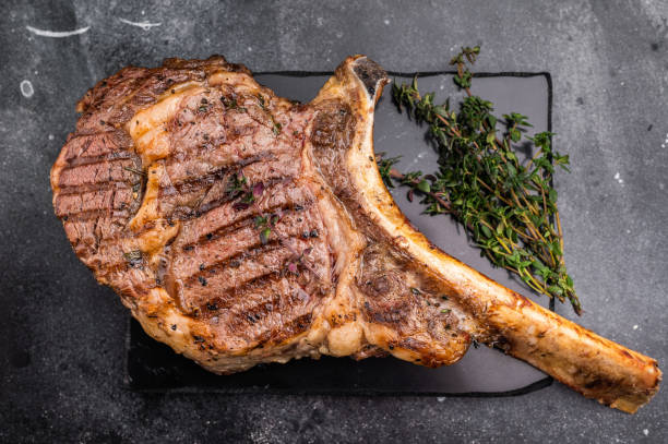 istock BBQ Grilled Tomahawk beef steak, cooked rib eye with bone on marble board. black background. top view 2204874080