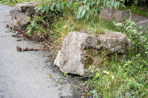 istock large grey boulders rocks placed next to tarmac road to security stop parking and access 2204874107