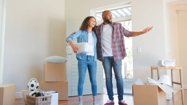 istock Loving Couple Standing In New Home On Moving Day Surrounded By Boxes 2204874184
