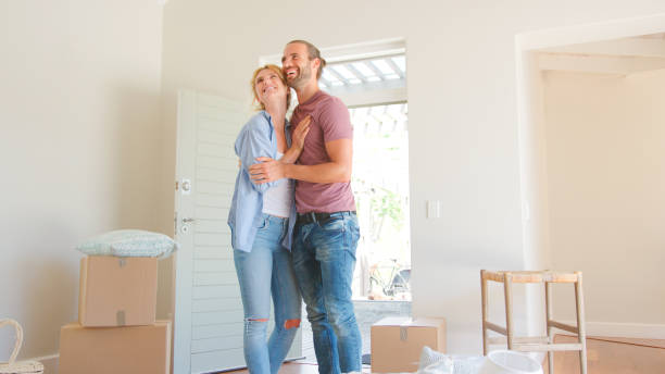 istock Loving Couple Standing In New Home On Moving Day Surrounded By Boxes 2204874288