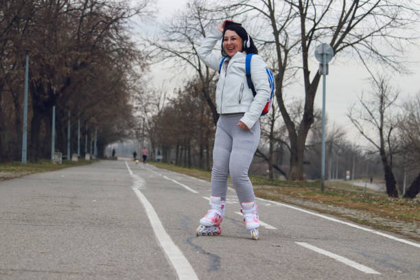 Beautiful blond woman with rollerblade inline skates on the road. Attractive sportswoman in sport clothing skating at sunset.