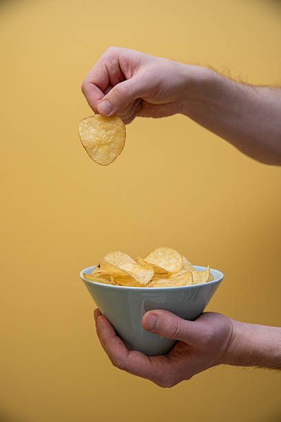 istock hand getting some potato chips out of a bowl 2204876821