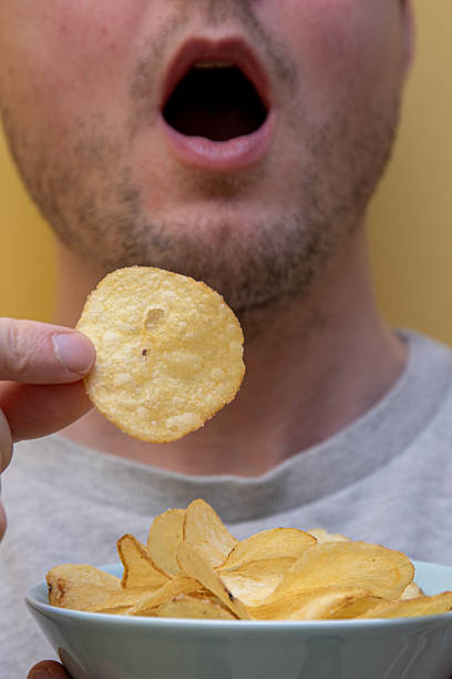 istock man eating potato chips. unhealthy eating concept. 2204876827