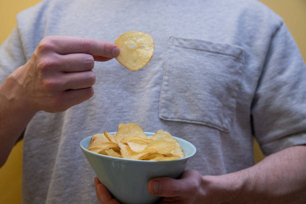 istock man eating potato chips. unhealthy eating concept. 2204876832