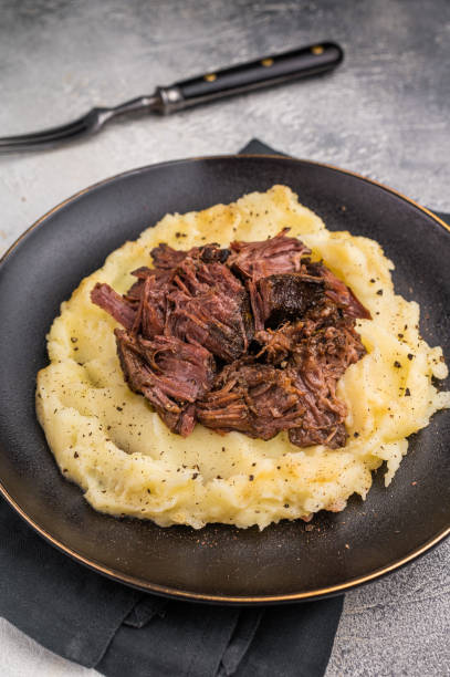 istock German Braised Beef Cheek, Slow cooked meat with smashed potatoes on a plate. grey background. top view 2204879126