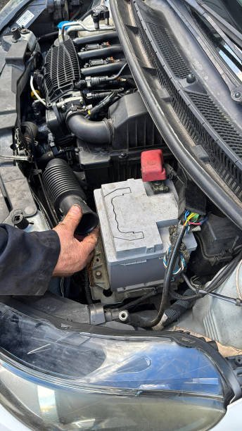 istock Full frame image of unrecognisable car mechanic wearing blue overalls working on car engine, oily hands, open car bonnet displaying engine, air intake pipe being tightened with plastic cable tie by vehicle mechanic, elevated view focus on foreground 2204882218