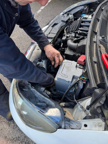 istock Image of unrecognisable car mechanic wearing blue overalls working on car engine, oily hands, open car bonnet displaying engine, air intake pipe being tightened with plastic cable tie by vehicle mechanic, elevated view focus on foreground 2204882223