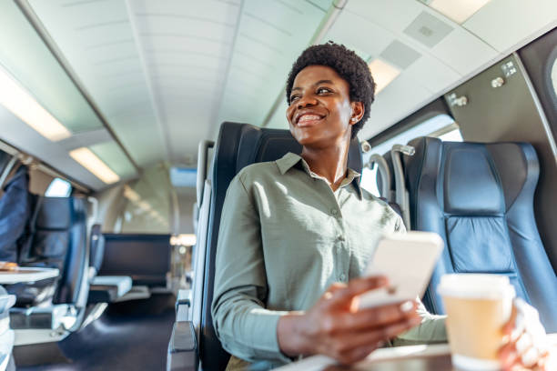 Smiling Woman Working on a Train with Smartphone and Coffee