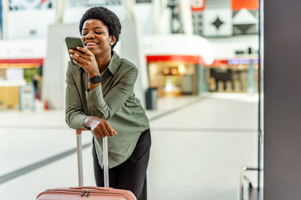 Smiling Woman Uses Smartphone While Traveling at a Modern Public Location