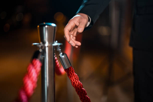 istock Close-Up of Male Security Guard's Hand Outdoors Holding Red Rope Under Dim Lighting 2204892492