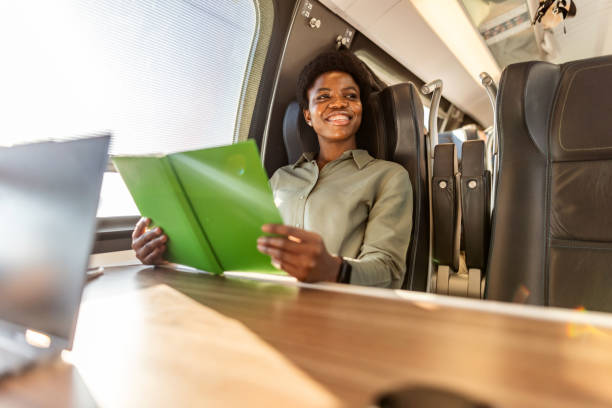 istock Businesswoman Smiling While Working on a Train Journey With Documents 2204892537