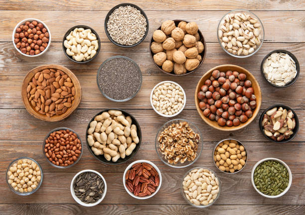 istock Peanut,hazelnut,walnut,almonds,pistachio,sunflower,pumpkin,chia,pecan and cashew mixed healthy nuts and seeds in various bowls on wooden background.Top view. 2204893268