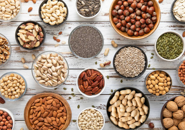 istock Mixed assorted raw healthy nuts and seeds in various bowls on light wooden table.Peanut,hazelnut,walnut,almonds,pistachio,sunflower,pumpkin,chia and cashew.Top view. 2204893290