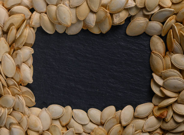 istock Creative display of pumpkin seeds arranged in a frame on a slate background for autumn festivities 2204893630