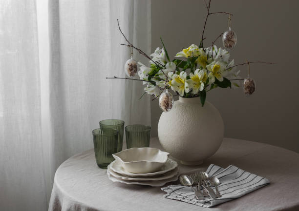 istock Easter table setting - plates, glasses, cutlery, Easter flower arrangement on a round table in the living room. 2204894320