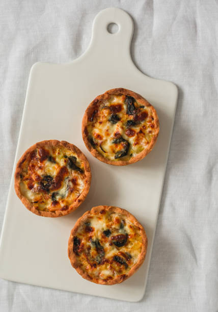 istock Mini pies with chicken, potatoes, spinach and leeks on a ceramic cutting board on a light background, top view 2204894339