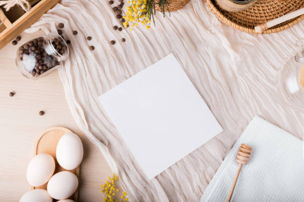 istock Top view of a kitchen table white sheet for text, featuring a light wooden surface with a crumpled white fabric laid across it. A jar of peppercorns is spilled nearby.Place for text, copyspace 2204895981