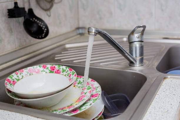 istock Dishwashing: Hand with pink sponge washing dishes in kitchen sink 2204898116