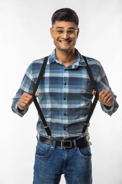 Portrait of young man dressed in suspenders smiling and posing against white background