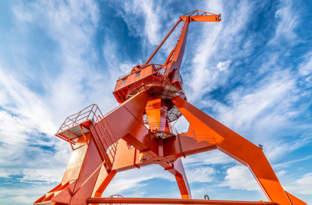 Close-up of a vibrant red harbor crane, starkly contrasted against the clear blue sky.