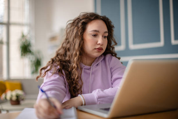 istock Plus size young woman working at home in comfortable living space while focused on laptop 2204900720